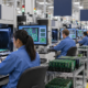Technicians inspecting circuit boards on an electronics manufacturing line